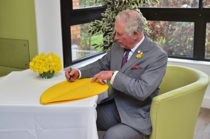 The Prince of Wales signs a petal as part of the Great Daffodil Appeal during a visit to the Marie Curie Hospice in Cardiff and the Vale, Wales.