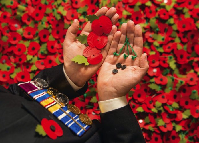 Army veteran Shane Crowhurst pieces together a paper poppy at the Royal British Legion Poppy Appeal in Aylesford, Kent, which is one of the thousands of paper poppies that will be recycled through Sainsbury's after Armistice Day this year, 2014
