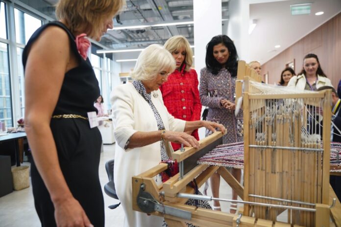 The Queen, watched by Brigitte Macron (second right), and Global Chief Executive officer of Chanel, Leena Nair (right), tries her hand at weaving tweed on a traditional loom in the Maison Lesage, during her visit to la Galerie du 19M in Paris, on day two of the State Visit to France. September 21, 2023.