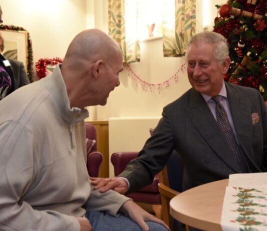 Sue Ryder Celebrates Sovereign News His Majesty spends time with a patient on a previous visit to Sue Ryder Leckhampton Court Hospice as during his Patronage as Prince of Wales. Credit: Rob Lacey